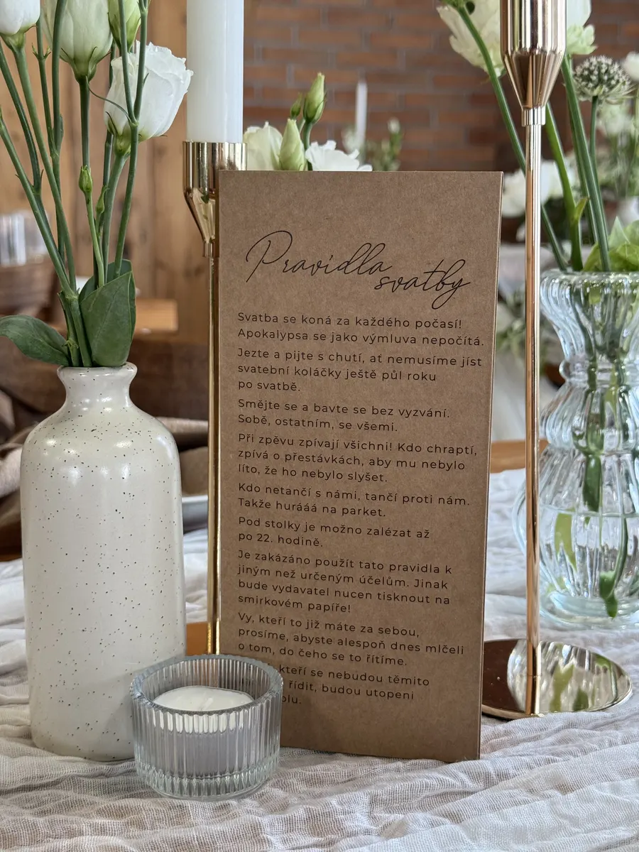 Detail stolu s menu, vázou a bílými květy