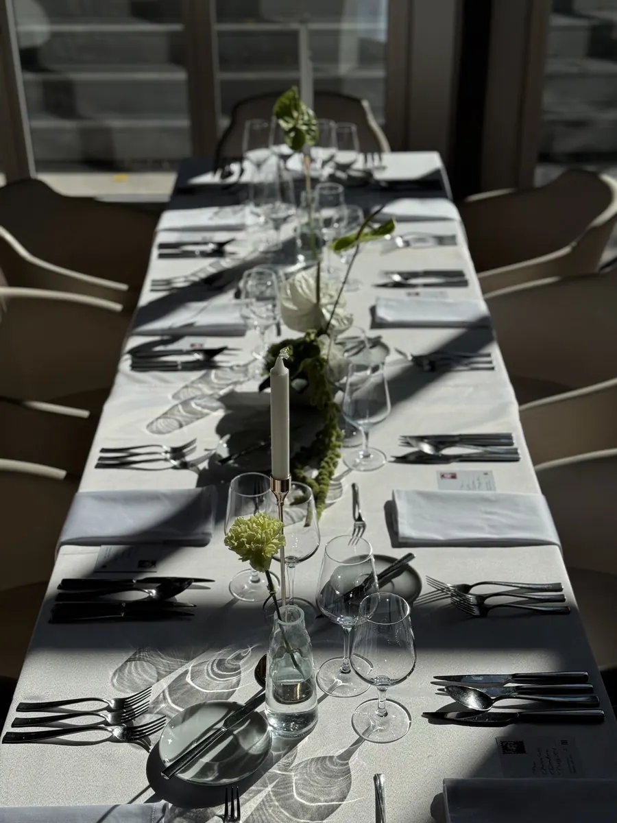 Slavnostně prostřené stoly v prosvětlené restauraci se stromy