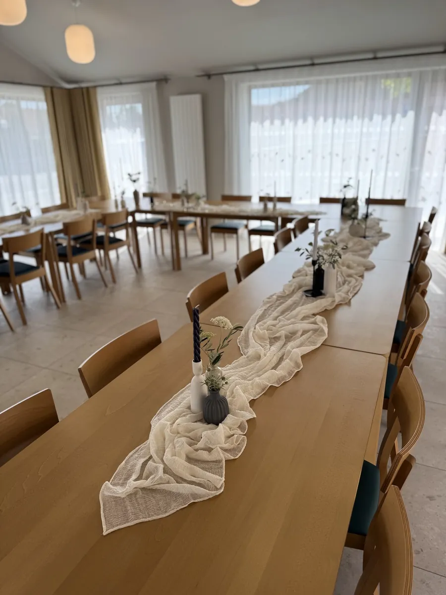 Dlouhá tabule s krémovým gázovým běhounem a vázami s kvítky